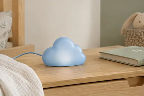 Veilleuse LED bleue en forme de nuage posée sur une table de chevet en bois clair